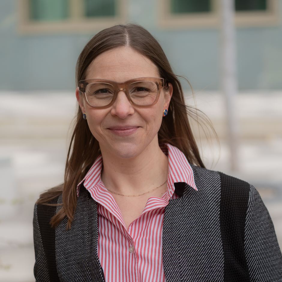 Maria Matthäus mit Brille, gestreifter Bluse und grauer Jacke, lächelnd