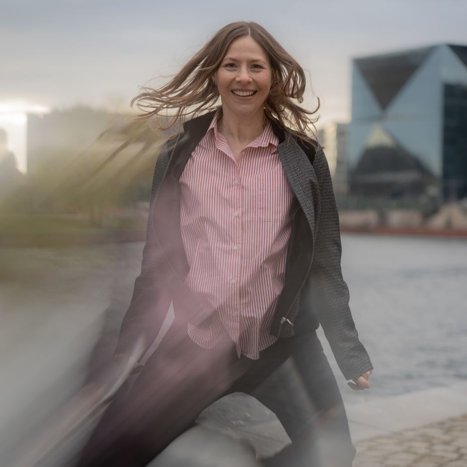 Maria läuft lachend am Ufer der Spree, die Haare wehen